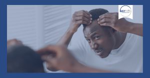 Black man checking receding hair line.